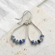 Silver earrings with blue beads on a white fabric background