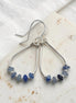 Silver earrings with blue beads on a white fabric background