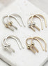 Four minimalist U-shaped hoop earrings with small metallic ball accents, shown in silver and gold finishes arranged on a white marble slab.