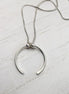 Silver necklace with a unique pendant on a white wooden surface