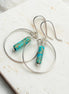 Silver hoop earrings with turquoise beads on a marble surface
