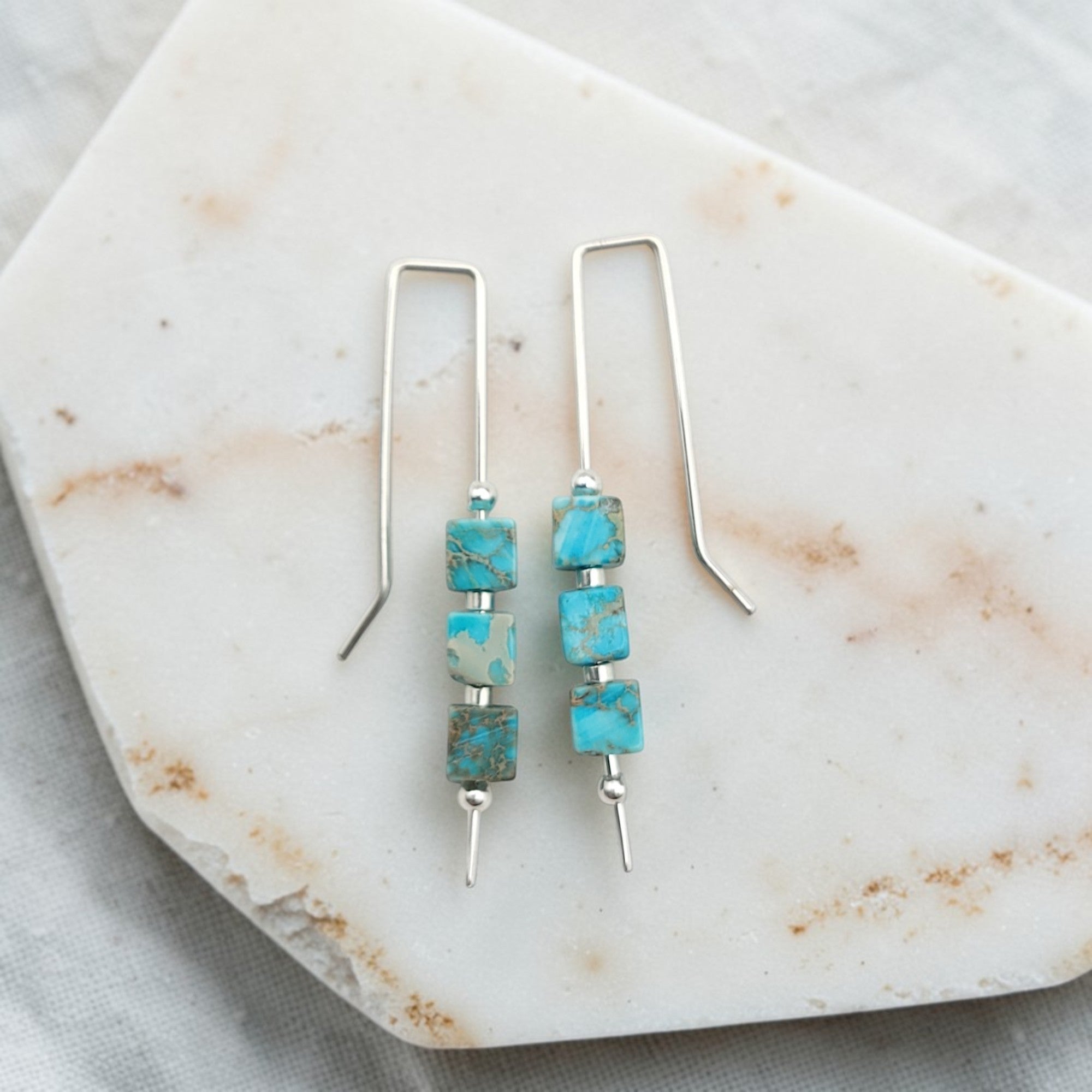 Turquoise beaded earrings on a marble surface