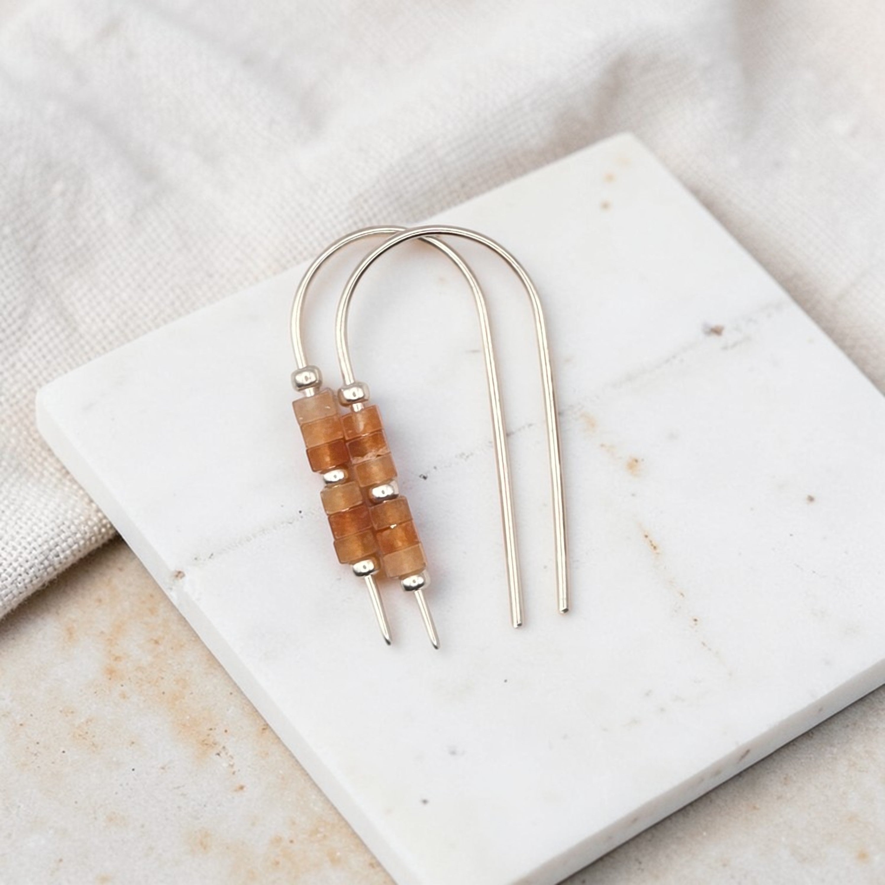 Pair of earrings with wooden beads on a marble surface