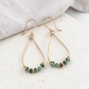 Gold earrings with turquoise beads on a light surface