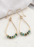 Gold earrings with turquoise beads on a light surface