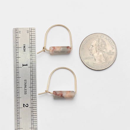Gold hoop earrings with cylindrical beads next to a ruler and quarter for scale on a white background