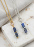 Two necklaces with blue bead pendants on a marble surface.