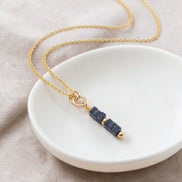 Necklace with blue beads and gold chain on a white dish