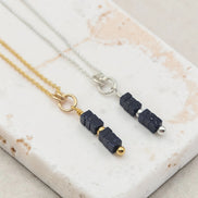 Necklace and earrings with blue stone beads on a marble surface