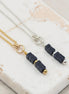 Necklace and earrings with blue stone beads on a marble surface