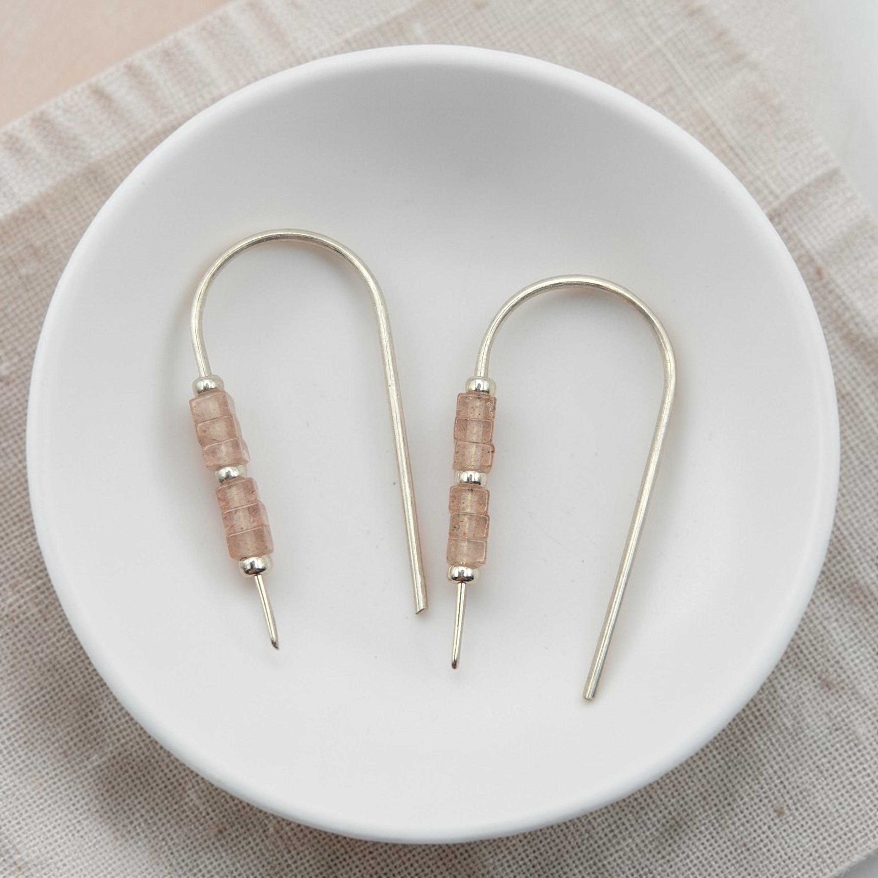 Pair of earrings with pink beads on a white plate