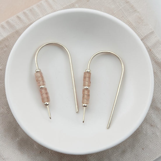 Pair of earrings with pink beads on a white plate