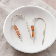 Pair of earrings with orange beads on a white plate