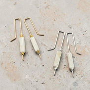 Set of jewelry-making tools with gold and silver hooks on a textured surface