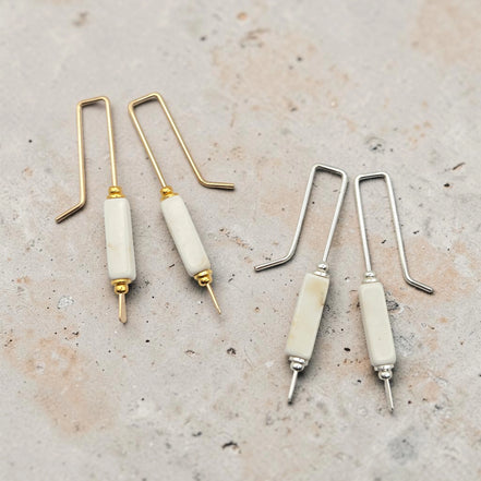 Set of jewelry-making tools with gold and silver hooks on a textured surface