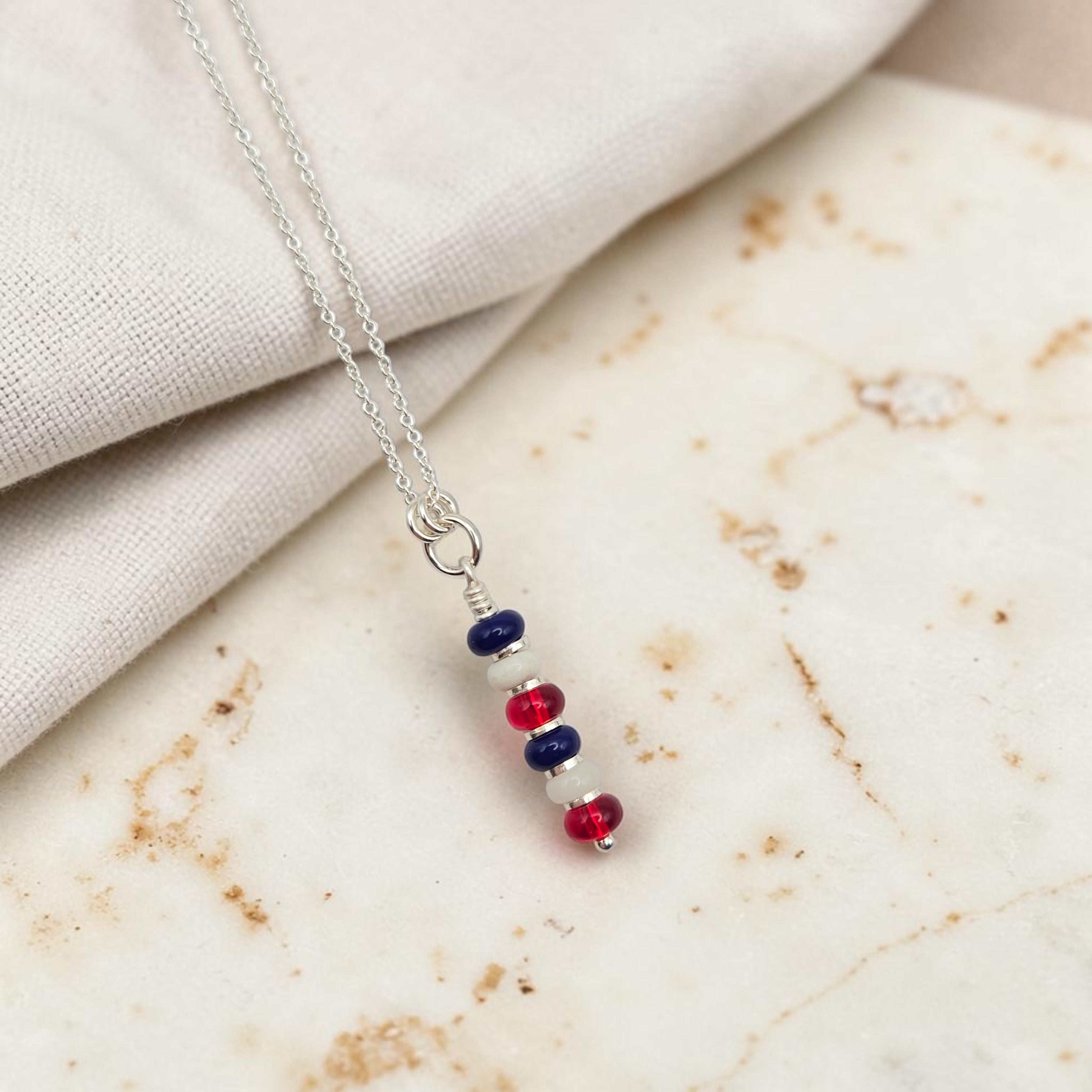 Necklace with red, blue, and silver beads on a marble surface