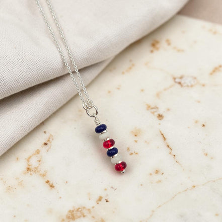 Necklace with red, blue, and silver beads on a marble surface