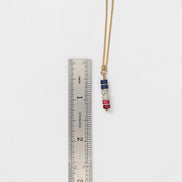 Necklace with colorful beads on a ruler for scale on a white background