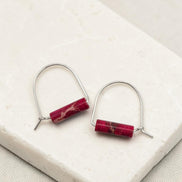 Pair of earrings with red cylindrical stones on a white surface