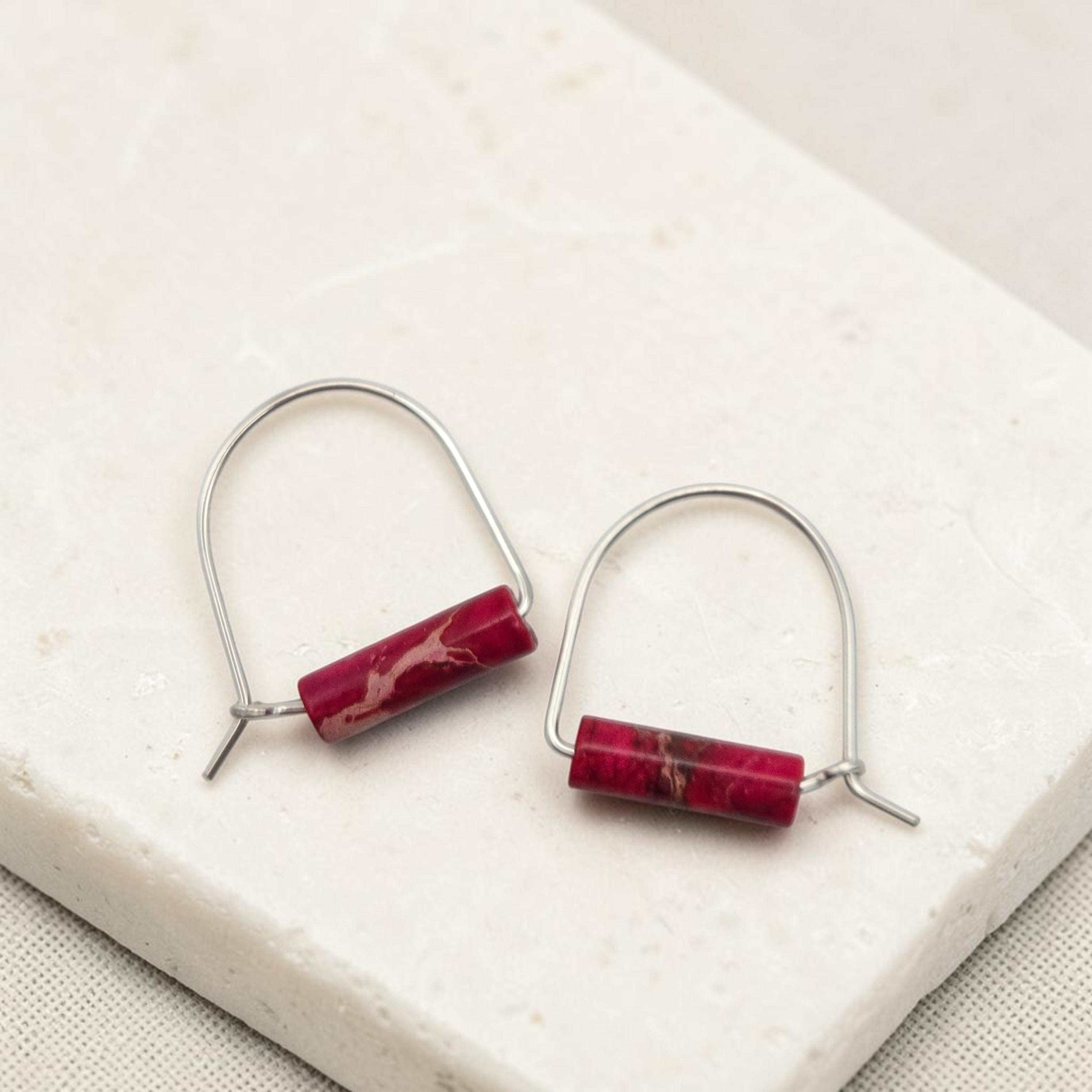 Pair of earrings with red cylindrical stones on a white surface