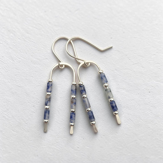 silver wishbone shaped earrings featuring blue spot jasper beads