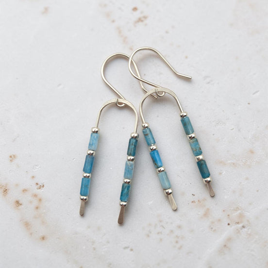 silver wishbone shaped earrings featuring blue apatite beads