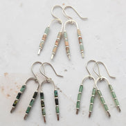 three pairs of silver wishbone shaped earrings. one featuring green aventurine beads, one featuring african turquoise beads and one featuring aqua terra jasper beads