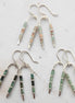 three pairs of silver wishbone shaped earrings. one featuring green aventurine beads, one featuring african turquoise beads and one featuring aqua terra jasper beads