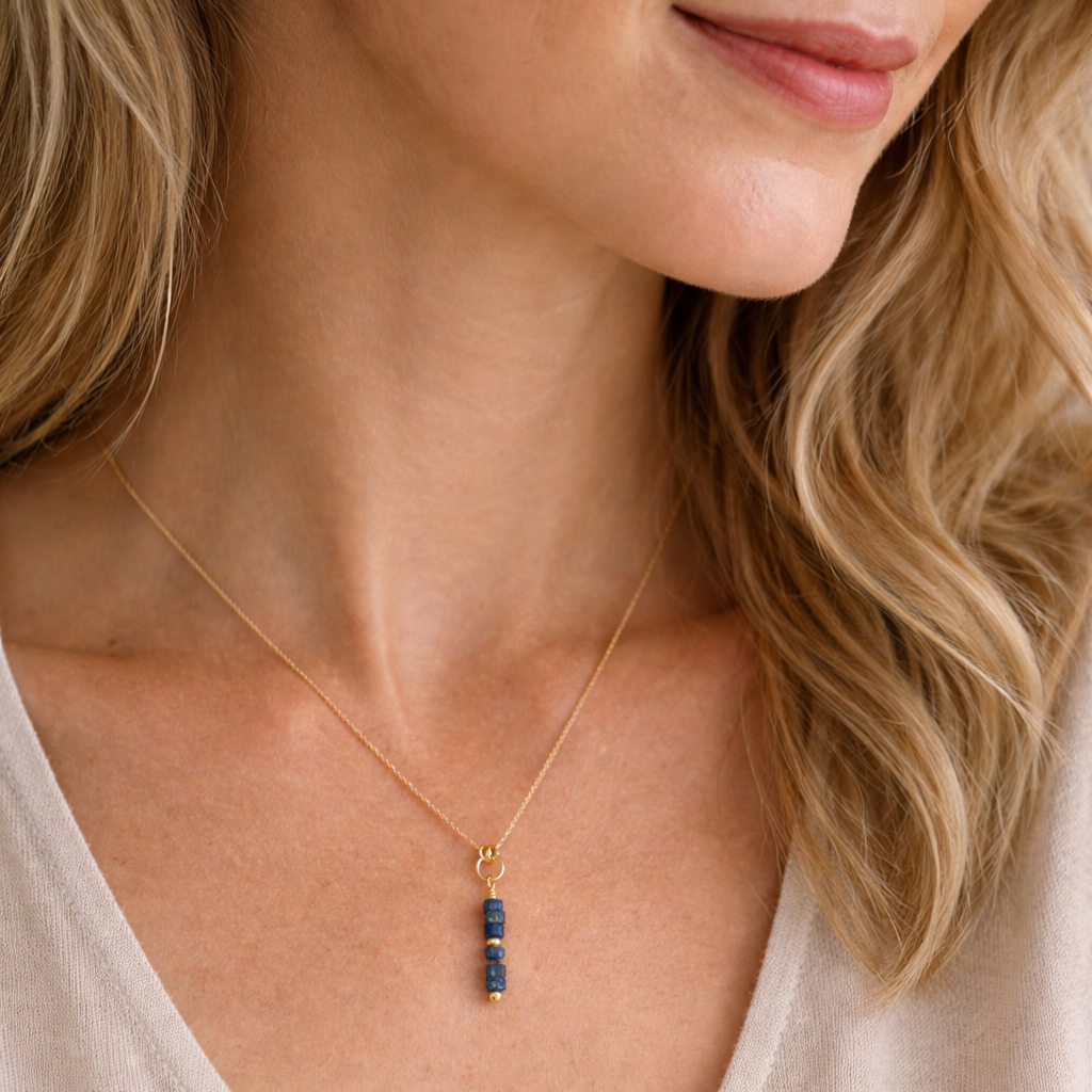 Close-up of a woman wearing a gold necklace with a blue pendant.