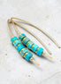 Turquoise beaded earrings with gold accents on a light gray background