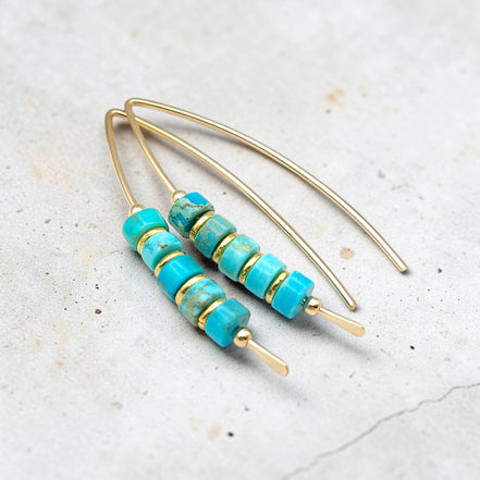 Turquoise beaded earrings with gold accents on a light gray background
