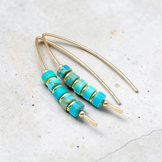 Turquoise beaded earrings with gold accents on a light gray background