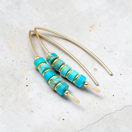 Turquoise beaded earrings with gold accents on a light gray background