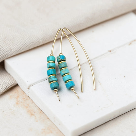 Turquoise beaded earrings on a marble surface