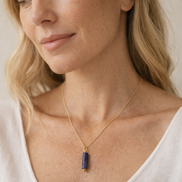 Woman wearing a gold necklace with a blue pendant