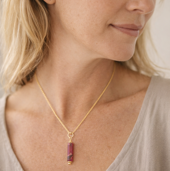 Woman wearing a gold necklace with a red pendant