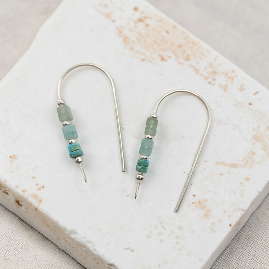 Pair of earrings with green beads on a marble surface