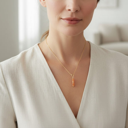 Woman wearing a gold necklace with a pendant in a neutral setting