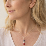 Woman wearing a gold necklace with a colorful pendant