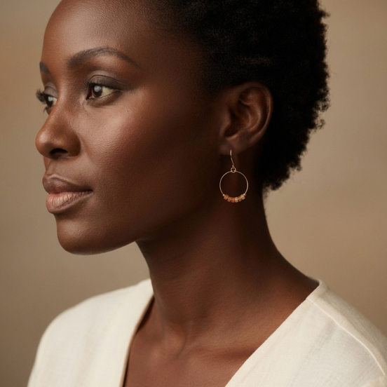 Woman wearing gold hoop earrings against a neutral background