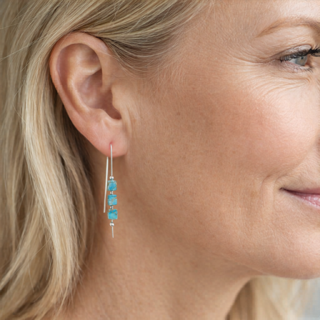 Close-up of a woman wearing turquoise earrings with a blurred background