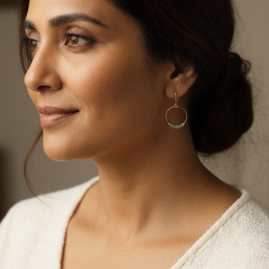 Close-up of a woman wearing gold hoop earrings with a neutral background