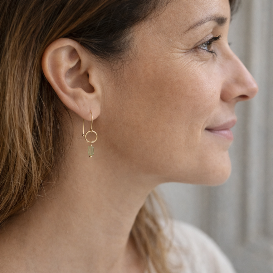Close-up of a woman wearing gold hoop earrings with a blurred background