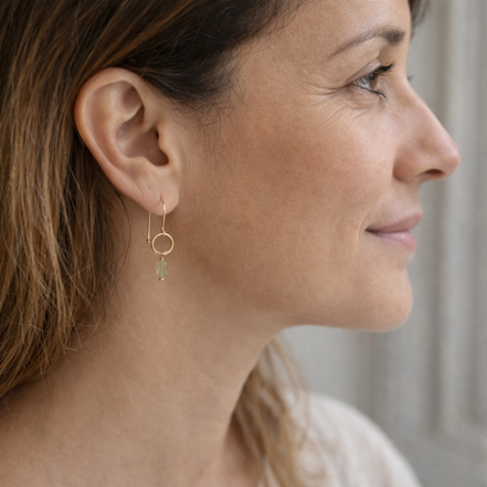 Close-up of a woman wearing gold hoop earrings with a blurred background
