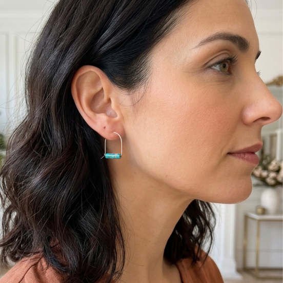 Woman wearing turquoise hoop earrings with a blurred indoor background