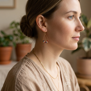 Woman wearing earrings and a necklace in a home setting with plants.