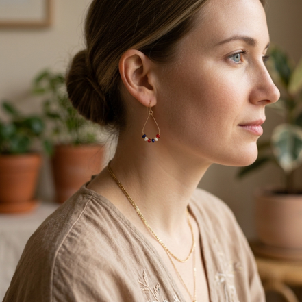 Woman wearing earrings and a necklace in a home setting with plants.