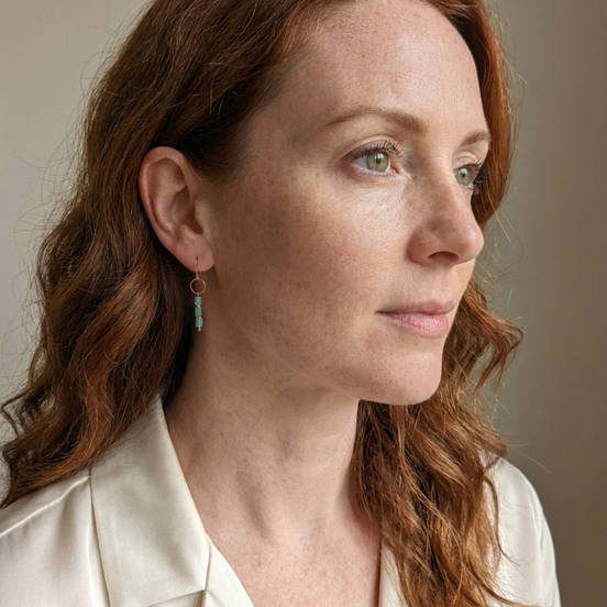 Bijou by SAM Riverstone dangle earrings featuring blue-green amazonite gemstones on gold hoops worn by a woman.