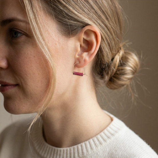Close-up of a woman wearing a red earring with a neutral background