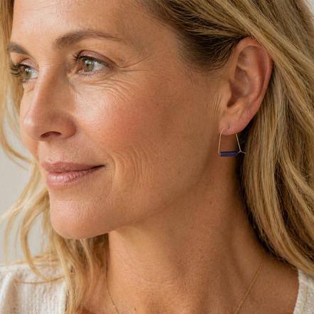 Close-up of a woman wearing a gold hoop earring with a blue accent.